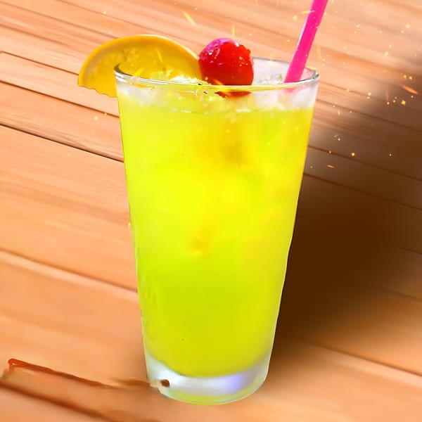 Bright green cocktail with ice, an orange slice, a cherry, and a pink straw on a wooden table.