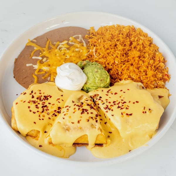 Juan Colorado's enchiladas covered in cheese sauce, with rice, refried beans, guacamole, and sour cream.